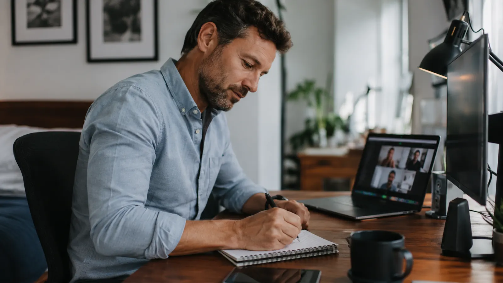 Remote worker at a clean home office desk writing in a reusable notebook instead of reaching for sticky notes