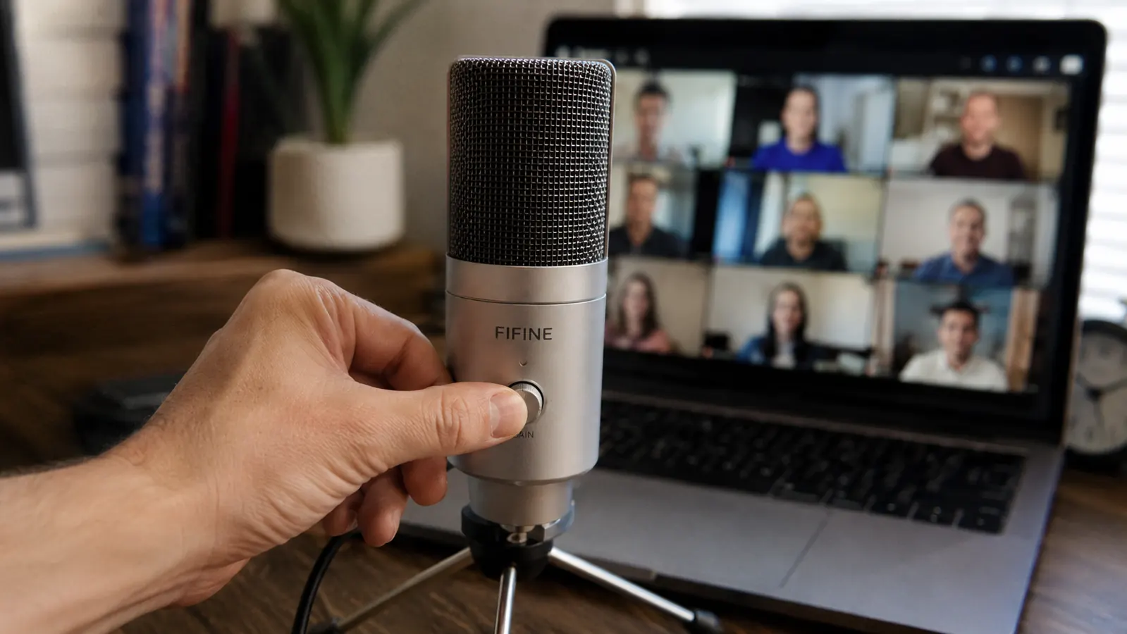 Hand adjusting the gain knob on the FIFINE K669S microphone during a video call