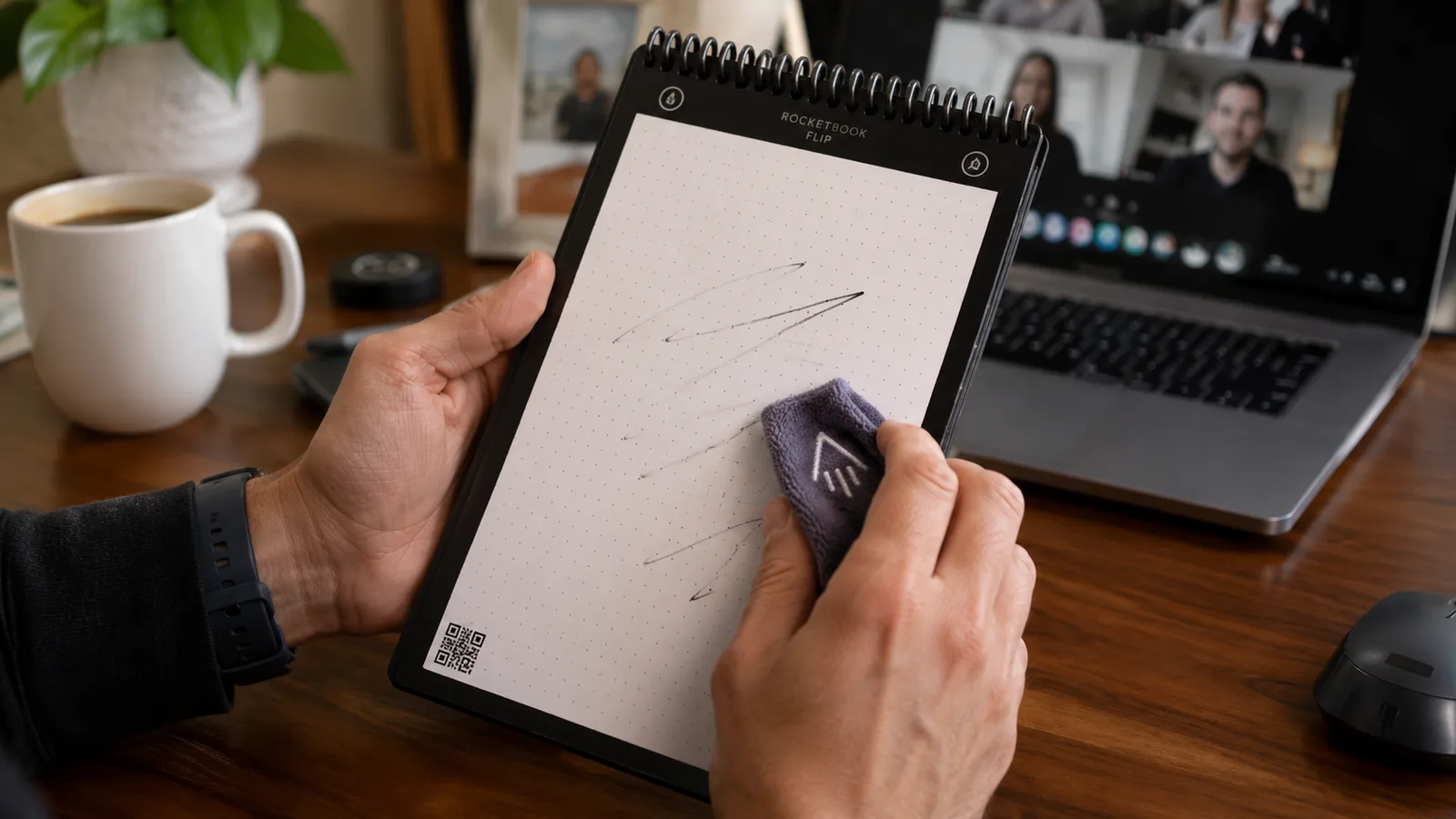 Hand wiping a page of the Rocketbook Flip clean with the included damp microfiber towel